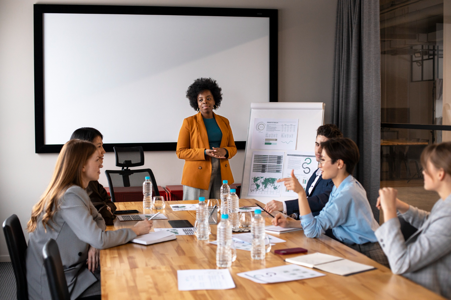 woman in orange blazer leading a board meeting
